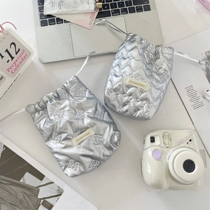 Detailed view of silver quilted drawstring bags with heart and bow patterns in a lifestyle setting