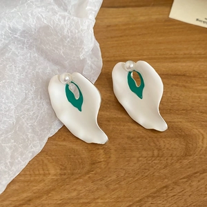 Detailed macro view of white calla lily stud earrings with pearl on a wooden background