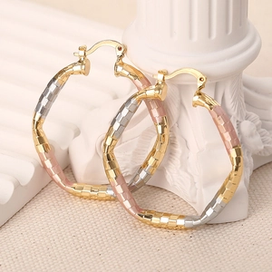 Detailed view of tricolor gold hoop earrings with textured checkerboard pattern