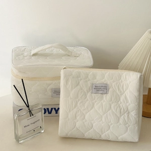 Detail of cream quilted heart makeup bag set with a vanity case and a zipper pouch