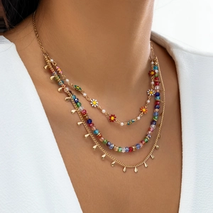 Detailed close-up of a three-layer bohemian gold necklace with colorful beads and daisies