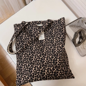Detailed view of large leopard print canvas tote bag with woven label on a white table