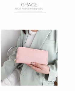 Detail of pink pebbled leather long wallet with gold zipper held by a model