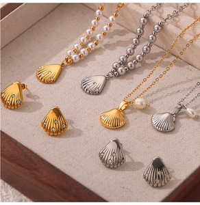 Shell shaped necklace and earring set with pearls displayed on a beige fabric jewelry tray