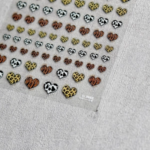 Detailed view of heart-shaped nail art stickers with leopard and cow print patterns