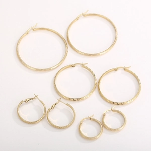 Close-up of four pairs of gold-plated hoop earrings with Greek key pattern engraving