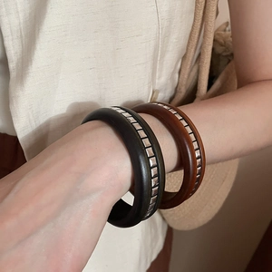 Gros plan de bracelets en bois rétro avec rivets argentés sur un poignet féminin