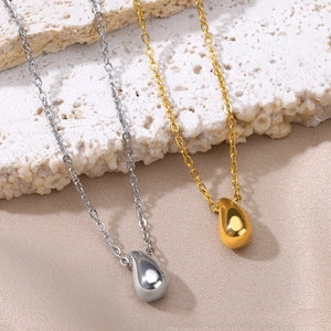 Detail view of mirror-polished gold and silver teardrop pendants on cross chains