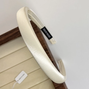 Close-up of cream satin padded headband texture on a wooden jewelry display tray