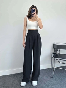 Gros plan d'un pantalon noir à taille haute et jambe large avec un débardeur blanc