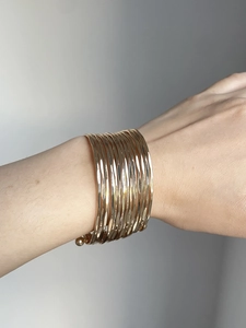 Close-up of a multi-layer golden wave textured cuff bracelet worn on a woman's wrist