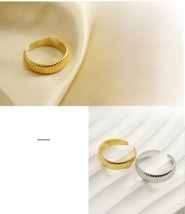 Detail of adjustable ribbed stainless steel ring showing vertical texture in gold and silver