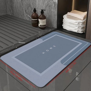 Dark grey diatomaceous earth bath mat with HOME text on stone floor, 50x80cm
