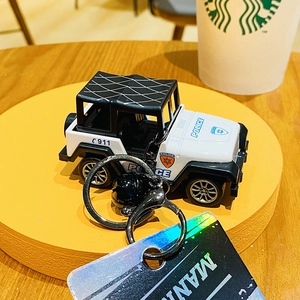 Close-up of black and white police jeep keychain with metal lobster clasp and matte bell