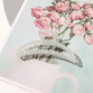 Detailed view of an elegant iridescent pearl claw clip with gold metal spring for long hair