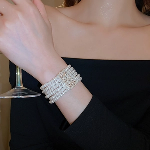 Detailed close-up of a luxury six-row pearl bracelet with a sparkling crystal-set centerpiece