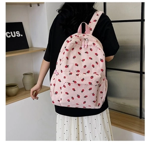 Pink corduroy backpack with strawberry print shown from a side back view on a model