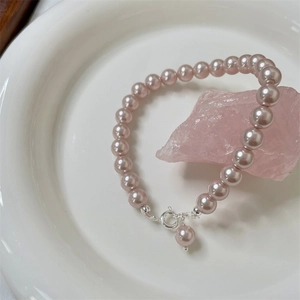 Detail of pink-purple 6-8mm pearl bracelet with S925 silver clasp on white ceramic dish