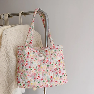 Detail of floral quilted cotton tote bag featuring a white French label on a soft fabric