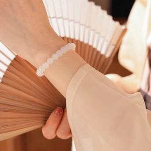 Detail of elegant white jasper beaded bracelet on wrist with traditional silk and wooden fan
