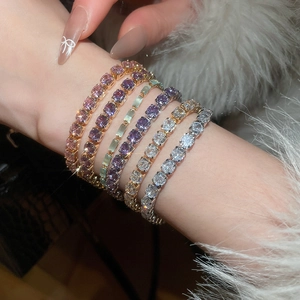 Macro detail of multi-colored zircon tennis bracelets on wrist with fluffy sleeve