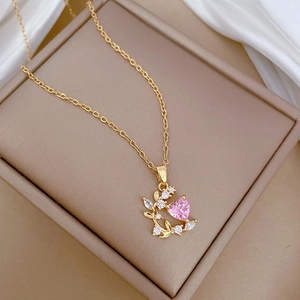 Elegant gold leaf necklace with a pink heart zircon and sparkling diamonds on beige box