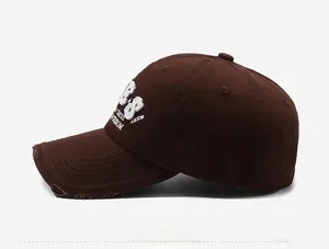 Close-up of white 3D embroidery and vintage distressed details on brown cotton baseball cap
