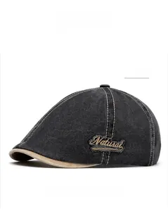 Detail of black denim flat cap featuring retro Natural embroidery and contrast beige piping