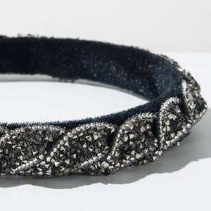 Dettaglio di cerchietto in velluto intrecciato con strass grigio scuro su sfondo bianco