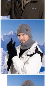 Close-up of gray knit hat, neck warmer and gloves set against a snowy mountain backdrop