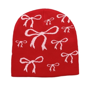 Macro detail of red knitted beanie featuring pink bow patterns and soft wool texture