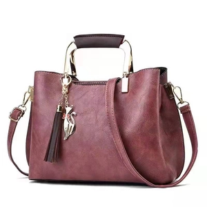 Burgundy PU leather handbag with top handle and cat tassel charm on white background
