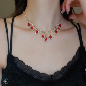 Close-up of gold fringe necklace with red teardrop stones and rhinestones on a model