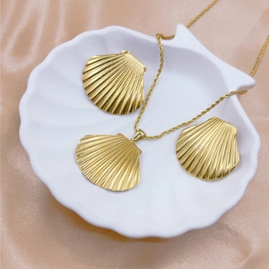 Elegant gold shell necklace and earrings set displayed on a white shell tray