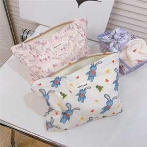 Close-up of floral and cartoon rabbit cotton pouches with zipper and woven label