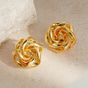 Elegant gold twisted flower stud earrings in metallic finish on minimalist stone background