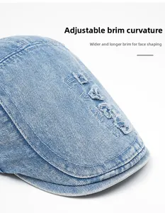 Detail of distressed brim and letter embroidery on blue denim duckbill flat cap