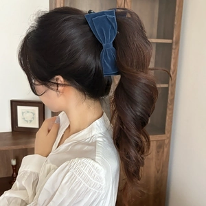 Detail view of a vintage navy blue velvet bow hair clip worn on model's head