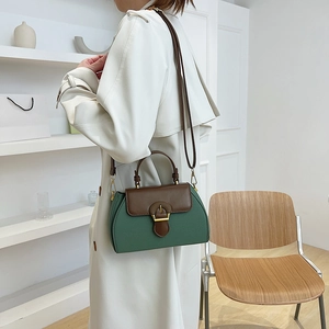 Detail of a vintage forest green and brown contrast leather handbag with golden buckle