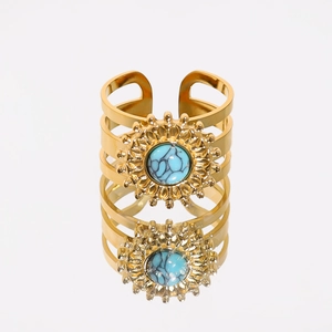 Close-up of gold titanium ring with turquoise stone and sunburst design on white base