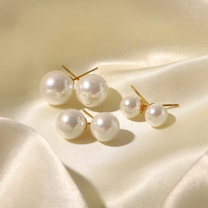 Three-piece set of elegant white pearl stud earrings with gold pins on silk fabric