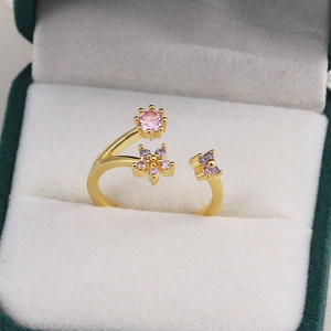 Détail macro d'une bague fleur dorée avec cristaux roses et violets en boîte de velours