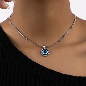 Close-up of model wearing evil eye pendant necklace with silver snake chain on black top