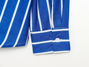 Gros plan du poignet d'une chemise à rayures bleues et blanches avec bouton blanc