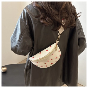Detailed view of a white cherry print crossbody bag worn by a model in a leather jacket