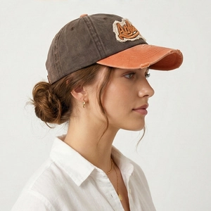 Detail view of washed cotton baseball cap with orange brim and distressed embroidery