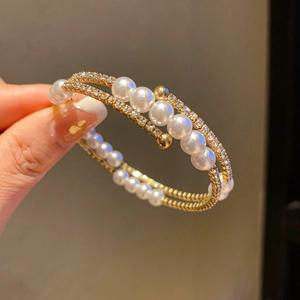 Detail of double-layer gold pearl bracelet featuring shimmering rhinestones on model's hand