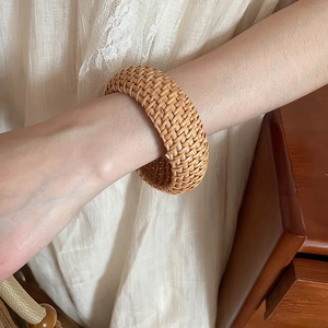 Gros plan d'un large bracelet en rotin tressé à la main au style bohème naturel
