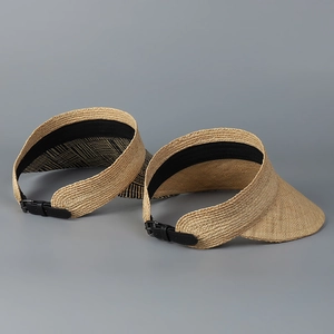 Detail view of woven raffia sun visor with adjustable black leather buckle strap