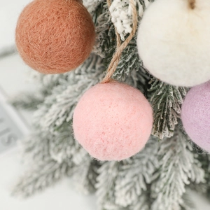 Colorful wool felt ball Christmas ornaments with twine hangers on tree branches